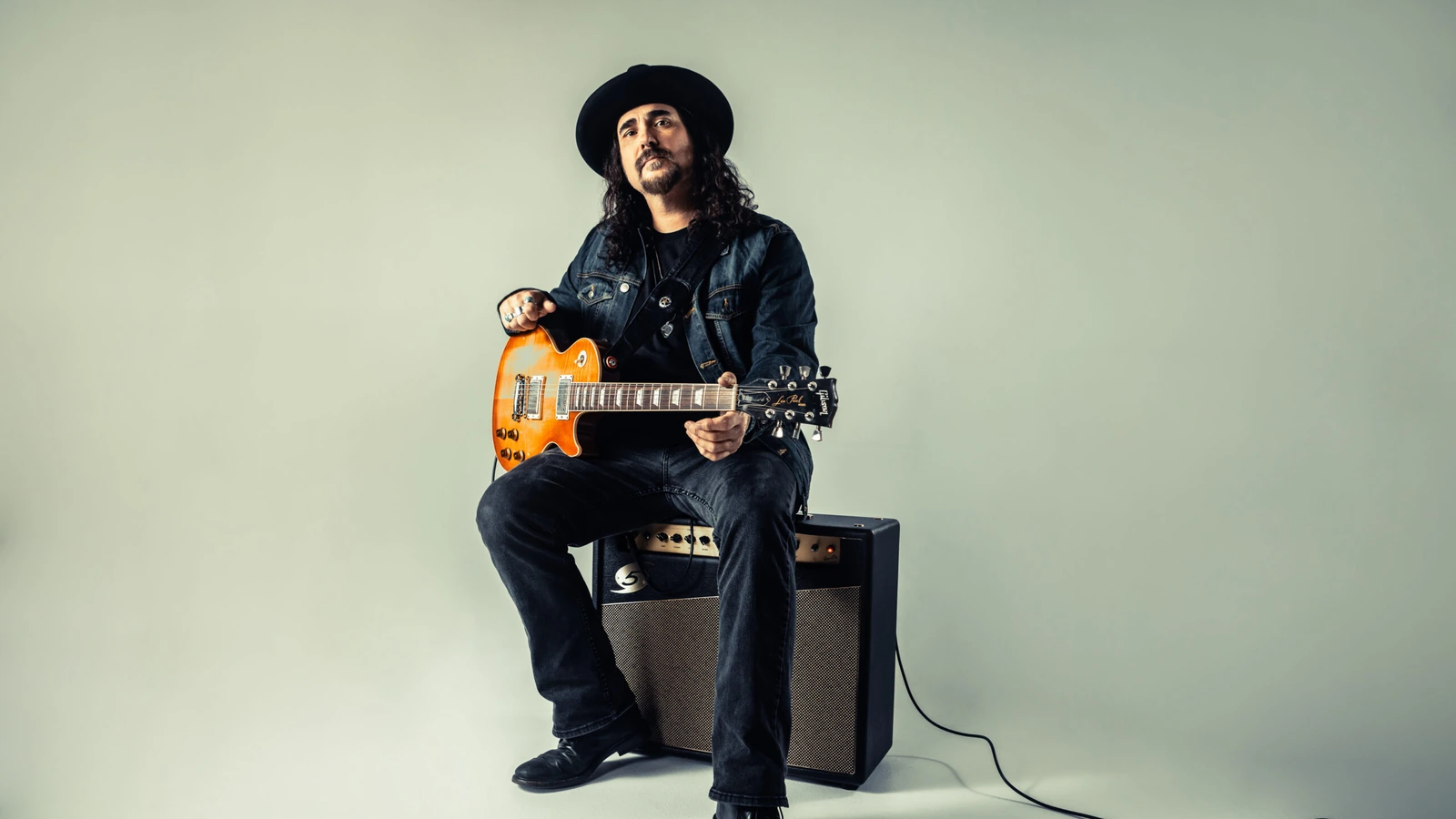 Alastair Greene holding an electric guitar in an archival publicity photograph.