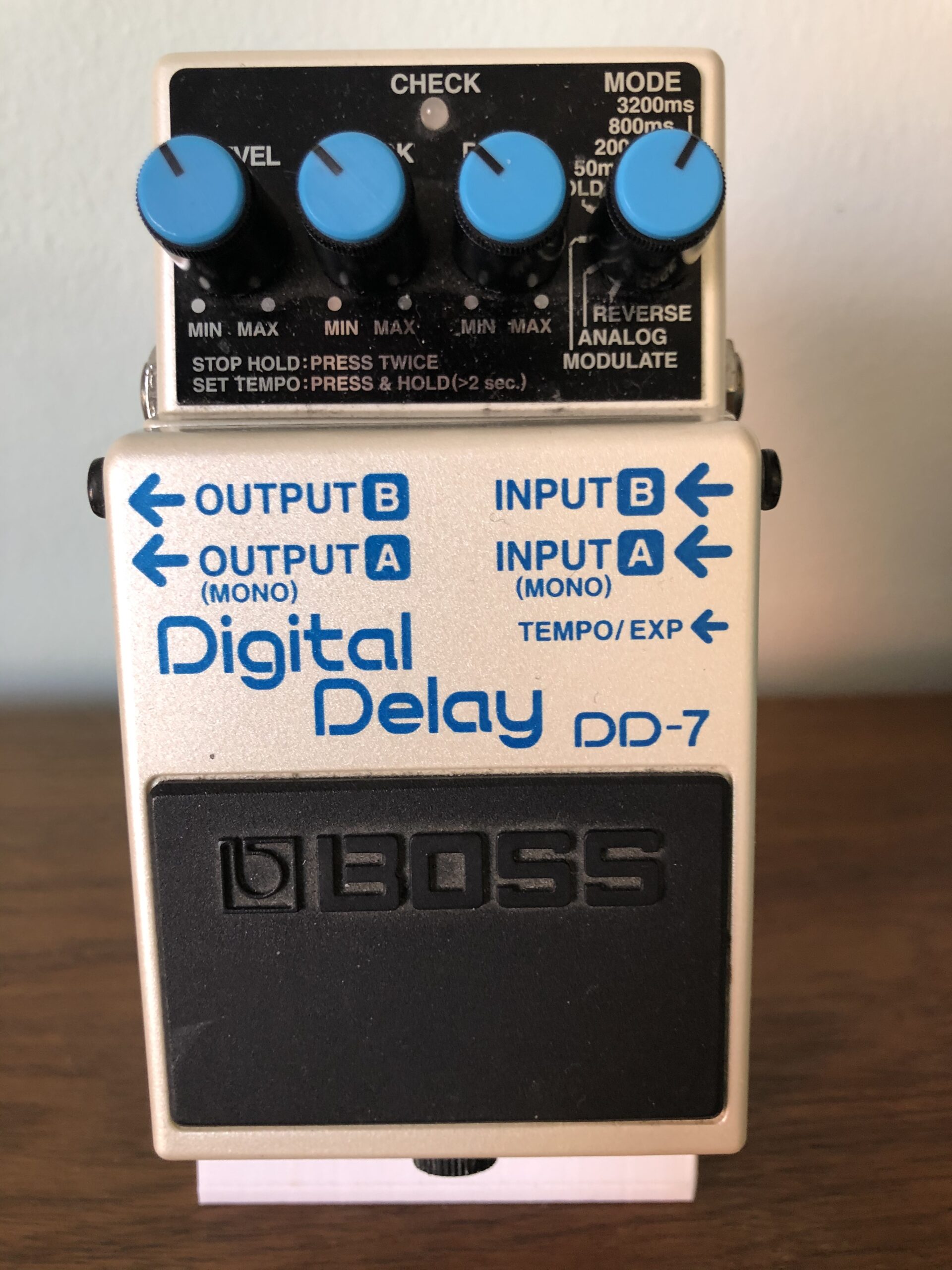 White Boss DD-7 Digital Delay pedal with four blue controls, stereo jacks and a tempo/expression input.
