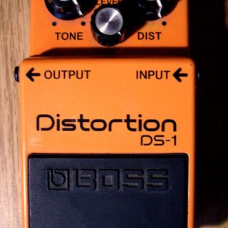 A used orange Boss DS-1 distortion pedal with three silver-topped control knobs.