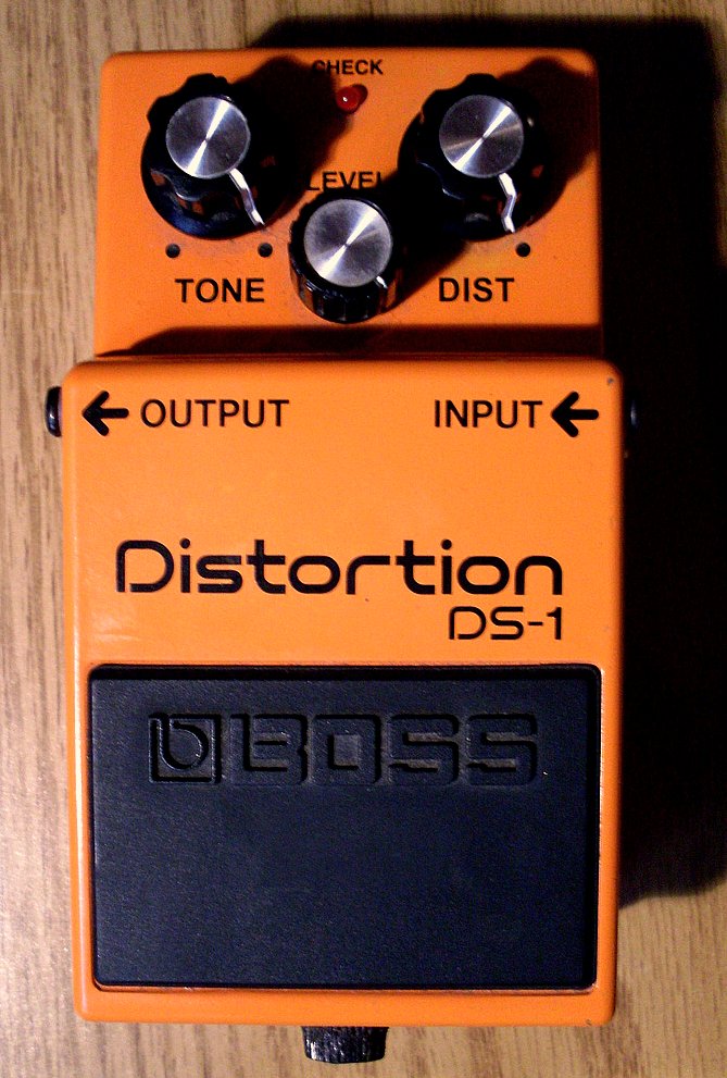 A used orange Boss DS-1 distortion pedal with three silver-topped control knobs.