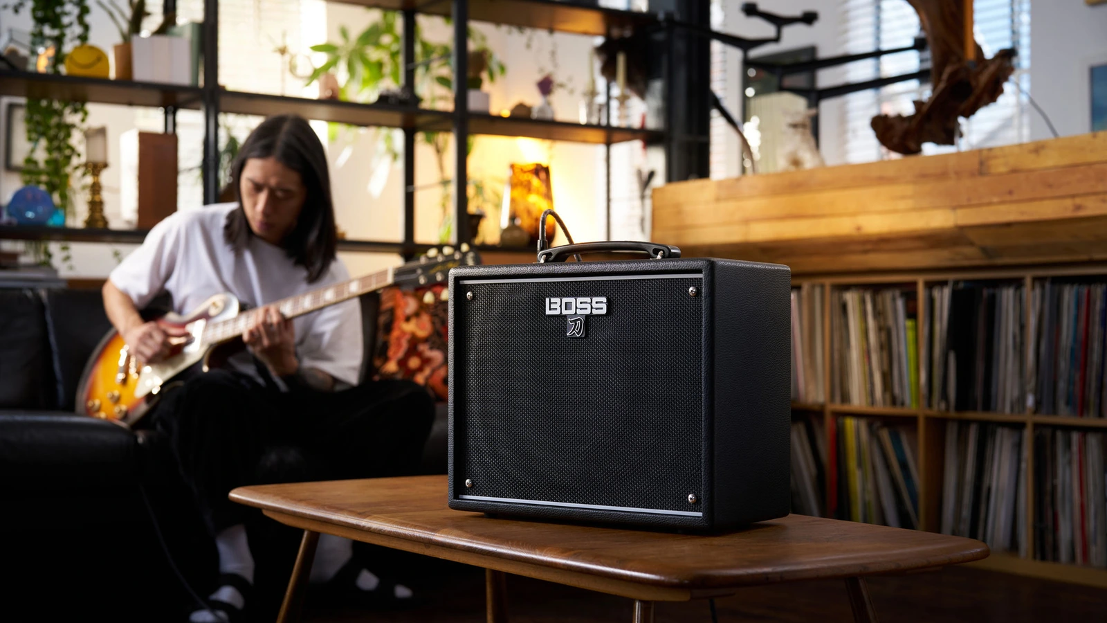 BOSS KATANA-25 amplifier with a guitarist playing in the background in a manufacturer promotional photograph