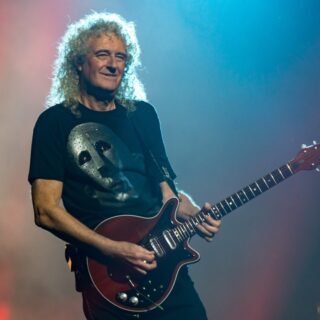 Brian May playing a red electric guitar at The O2 in London in December 2017.