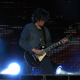 Dean DeLeo performing with Stone Temple Pilots at Ottawa Bluesfest in July 2009, with both hands and the complete black electric guitar visible.