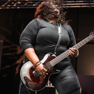 Diamond Rowe playing her Dark Rose Jackson signature guitar in a 2024 promotional photograph.