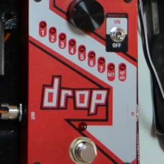 Complete red DigiTech Drop pitch-shifting pedal on a pedalboard, with tuning selector, momentary switch and footswitch visible.