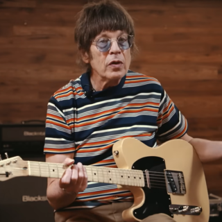 Elliot Easton seated with an electric guitar during an interview.