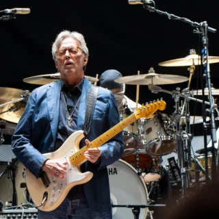 Eric Clapton playing a cream electric guitar at the Royal Albert Hall in 2023.