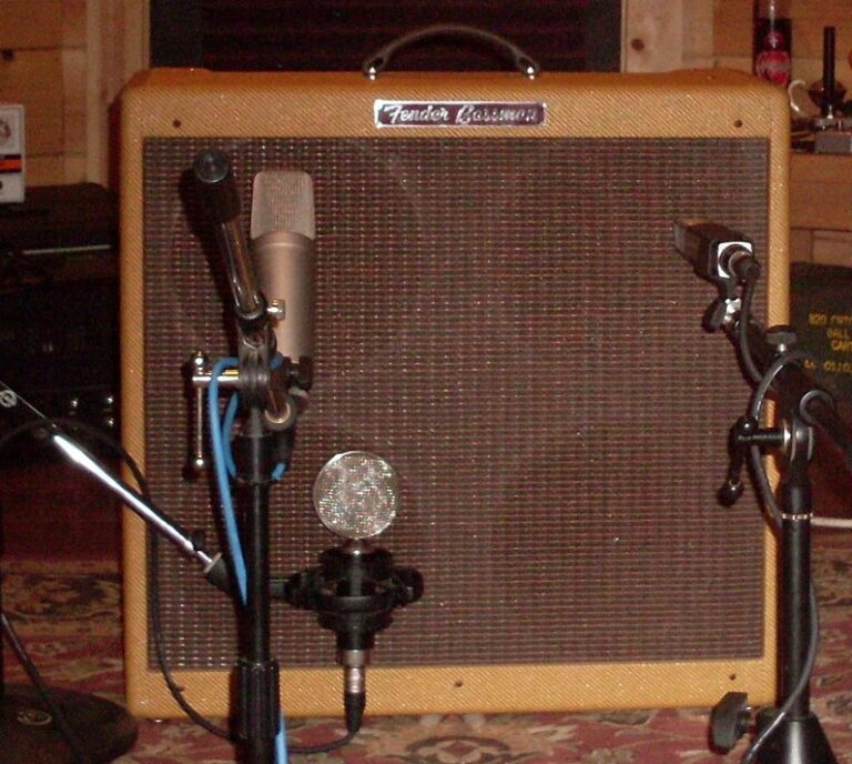 A tweed Fender Bassman combo set up with microphones in a recording studio.