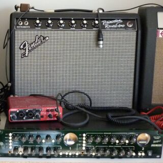 A Fender Princeton Reverb reissue behind cables and rack-mounted recording equipment.