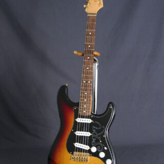 Front view of a sunburst Fender Stevie Ray Vaughan signature Stratocaster on a stand, with SRV pickguard and reversed gold tremolo.