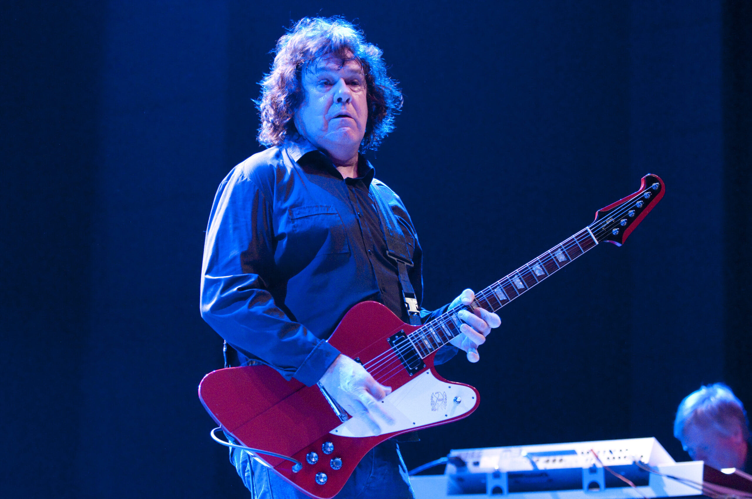 Gary Moore playing a red Gibson Firebird onstage in 2009.