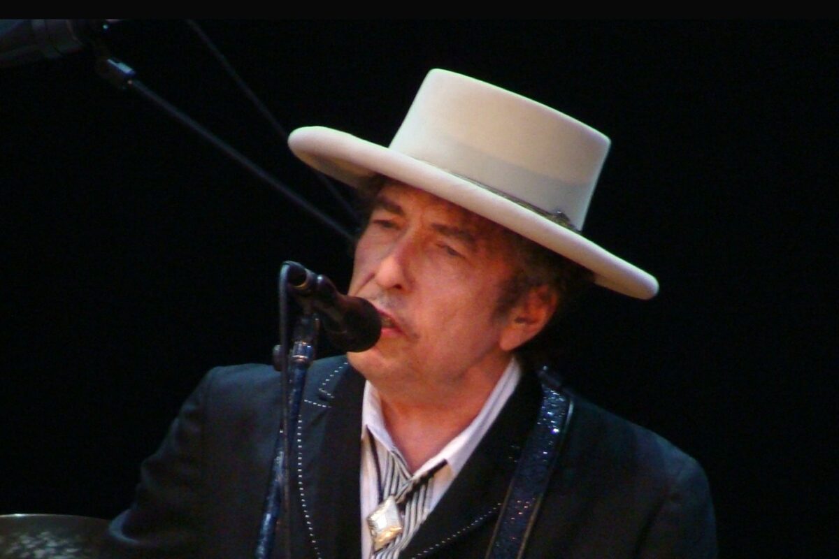 Bob Dylan in a white hat singing and playing guitar at the Azkena Rock Festival, 2010.