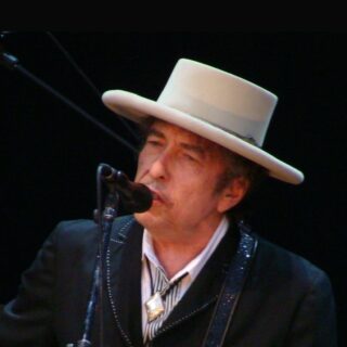 Bob Dylan in a white hat singing and playing guitar at the Azkena Rock Festival, 2010.