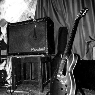 Black-and-white photograph of a Gibson ES-335 guitar beside a Randall amplifier, with the full guitar and photographer watermark visible.