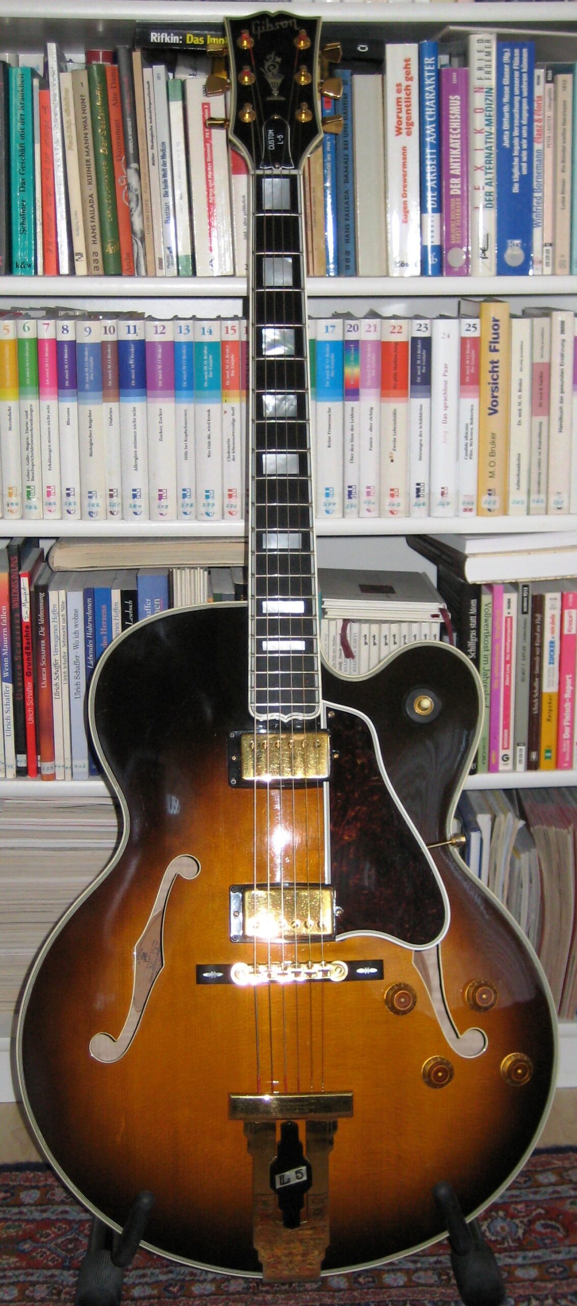 Complete tobacco-burst Gibson L-5 CES guitar on a stand, showing its headstock, neck, two humbuckers, controls and tailpiece.