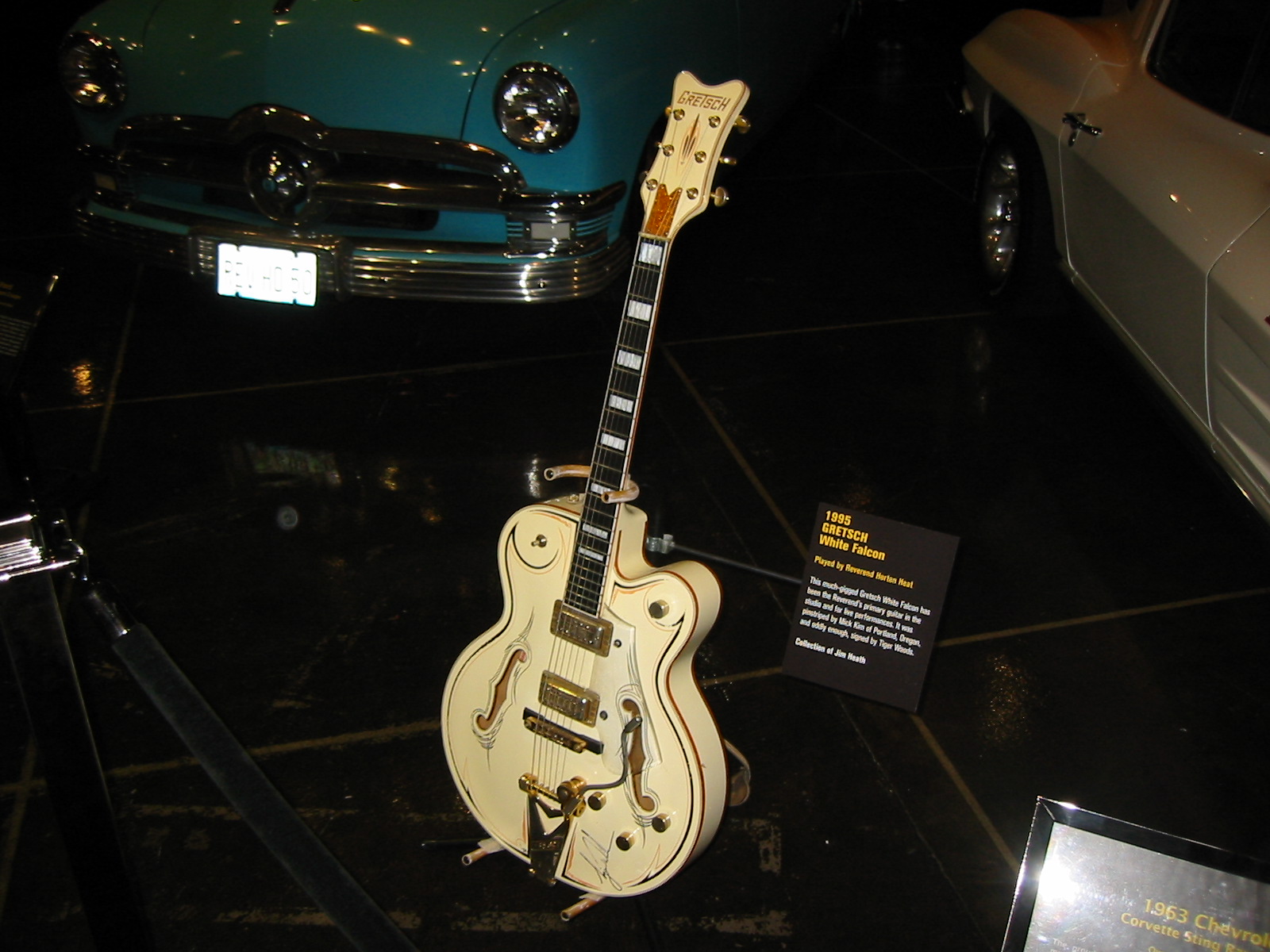 Complete cream-white Gretsch White Falcon with custom pinstriping and gold hardware, displayed on a stand among cars at the Petersen Automotive Museum.