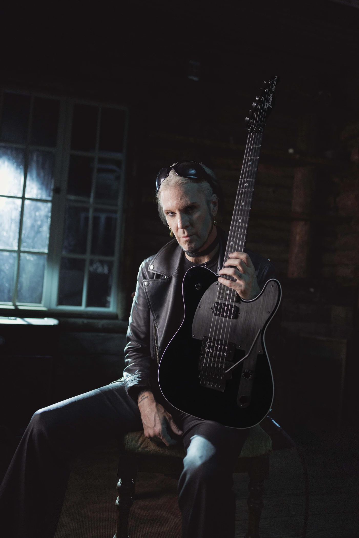 John 5 seated indoors holding his black Fender Custom Shop Phantom Telecaster upright.