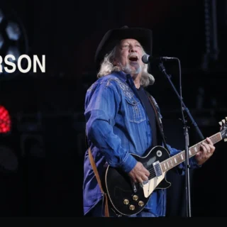 John Anderson playing a black electric guitar on stage at the 2017 CMA Music Festival
