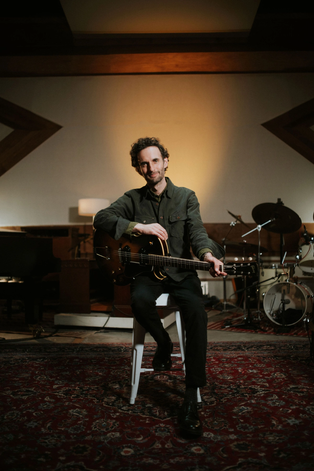 Julian Lage seated with a hollow-body electric guitar.