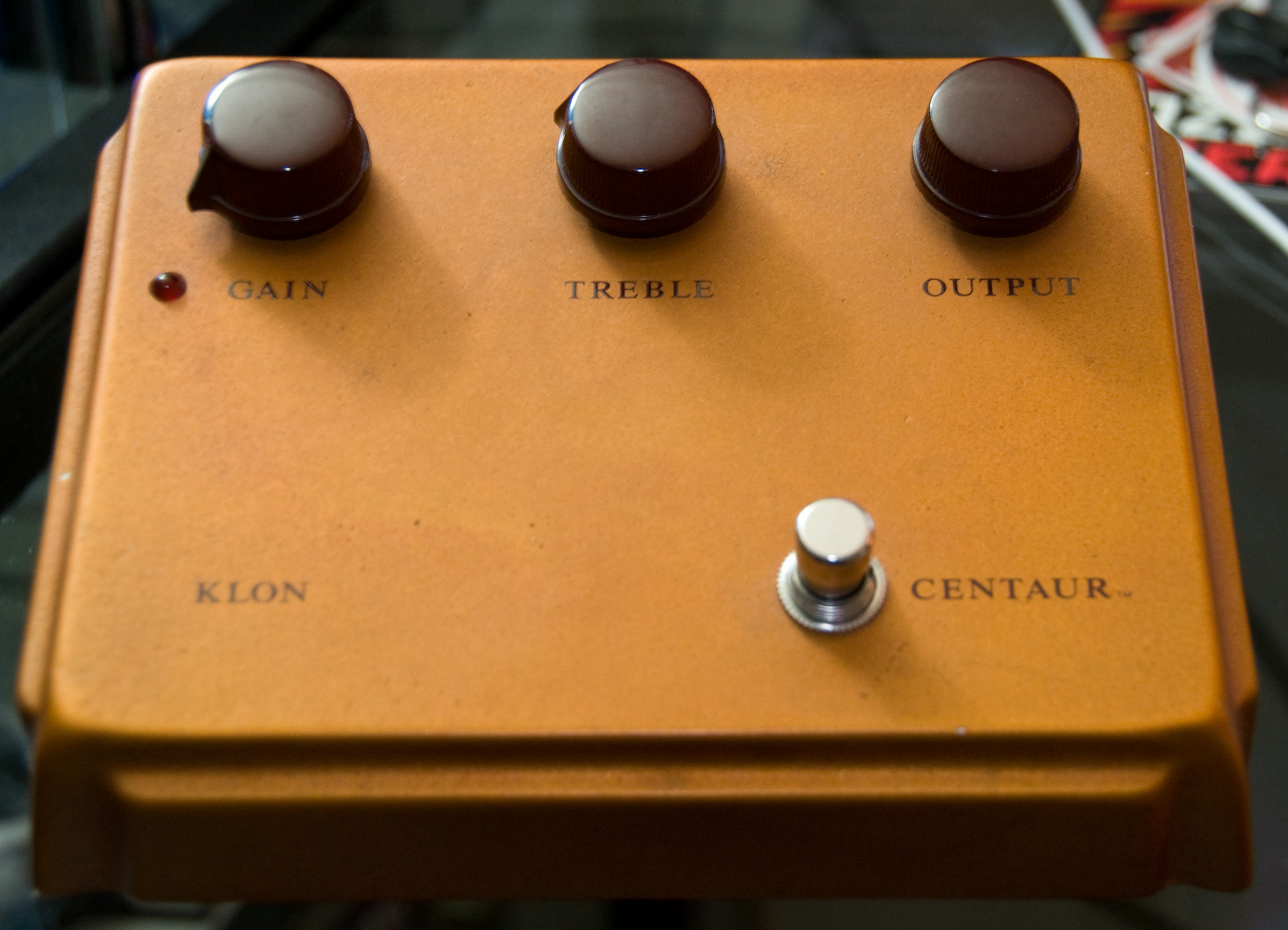 A gold-colored Klon Centaur pedal with its gain, treble and output knobs and footswitch visible.