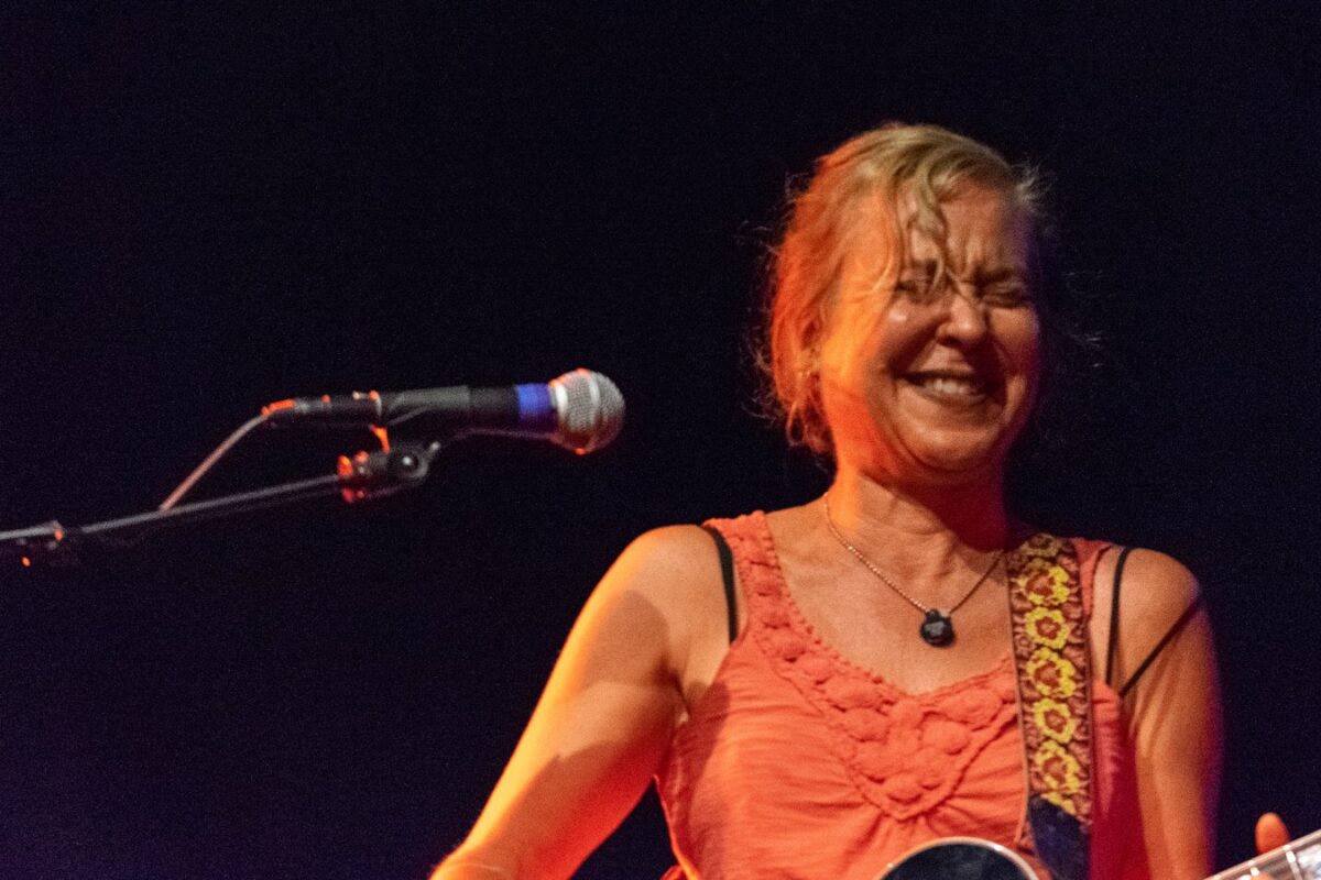 Kristin Hersh laughing on stage with her guitar beside a microphone during an Electric Trio concert in Somerville in 2019.