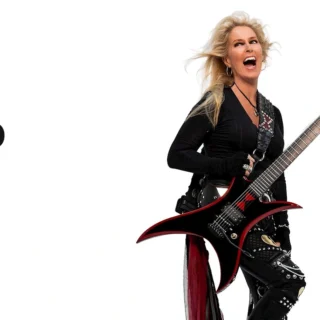 Lita Ford holding a black-and-red electric guitar in a white-background publicity photograph.