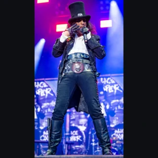 Alice Cooper sings into a microphone wearing a top hat on stage in Nuremberg in 2024.