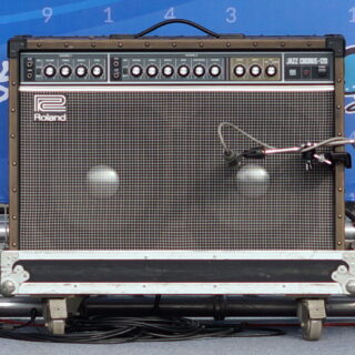 Complete Roland JC-120 Jazz Chorus amplifier on a road case, with a microphone in front of its speaker grille.