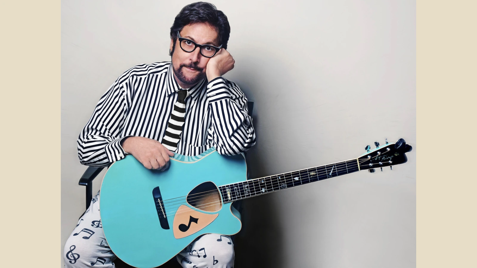 Stephen Bishop seated with a blue custom acoustic guitar