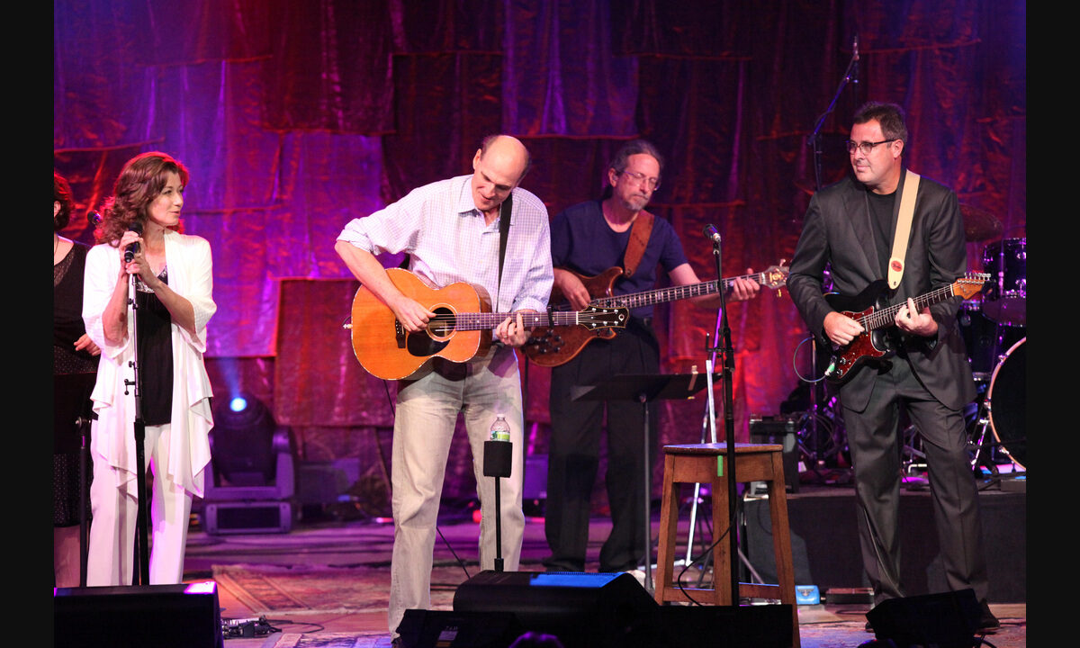 Musicians performing at Tanglewood in 2011, with Vince Gill at right playing a fully visible dark electric guitar; the entire source photograph is shown with dark side margins.