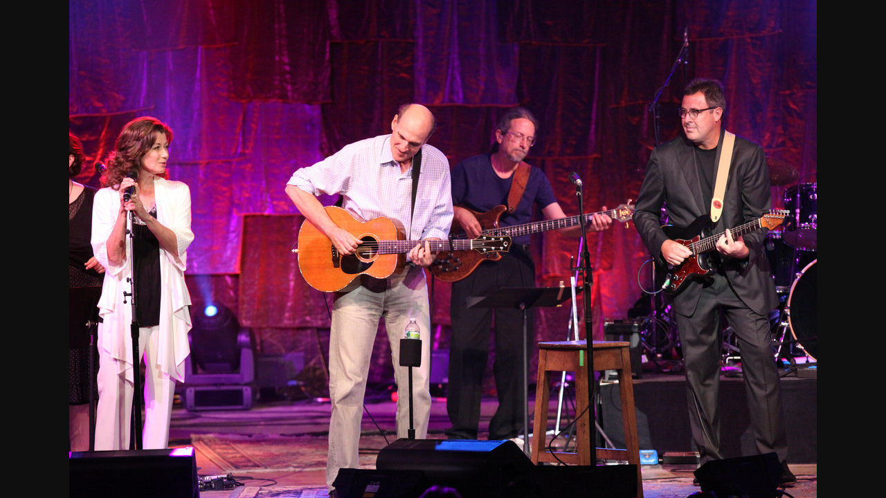 Musicians performing at Tanglewood in 2011, with Vince Gill at right playing a fully visible dark electric guitar; the entire source photograph is shown with dark side margins.