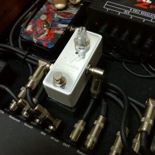 Complete silver Xotic EP Booster pedal connected among other pedals on a pedalboard.