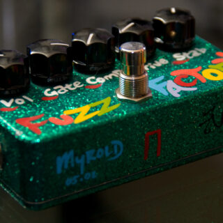 A green horizontal Z.Vex Fuzz Factory pedal with five control knobs, footswitch and input jack.